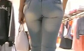 Two girls in the tight blue jeans are strolling over the shops followed by camera man